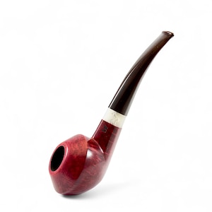 Op de afbeelding: Een gebogen tabakspijp met een diepe bordeauxrode ketel en een donkerbruin mondstuk. De pijp heeft een witte band met een reliëfontwerp bij het mondstuk. De ketel heeft een gladde, gepolijste afwerking.