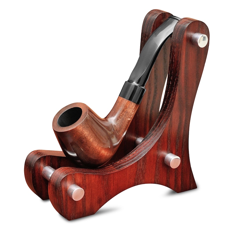 May include: A wooden tobacco pipe rests in a matching wooden stand. The pipe is a dark brown color with a black mouthpiece. The stand is a rich, reddish-brown with silver-colored pegs.