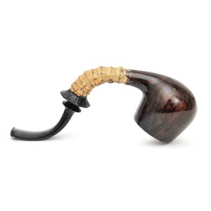 May include: A curved tobacco pipe with a dark brown bowl and a black stem. The stem is connected to a light tan, textured section. The pipe has a unique, artistic design.