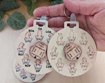 May include: Wooden keychains with a round design featuring anatomical illustrations and text. The keychains have a light wood finish and include a rotating central piece with labeled bone diagrams. The keychains are held by a person.