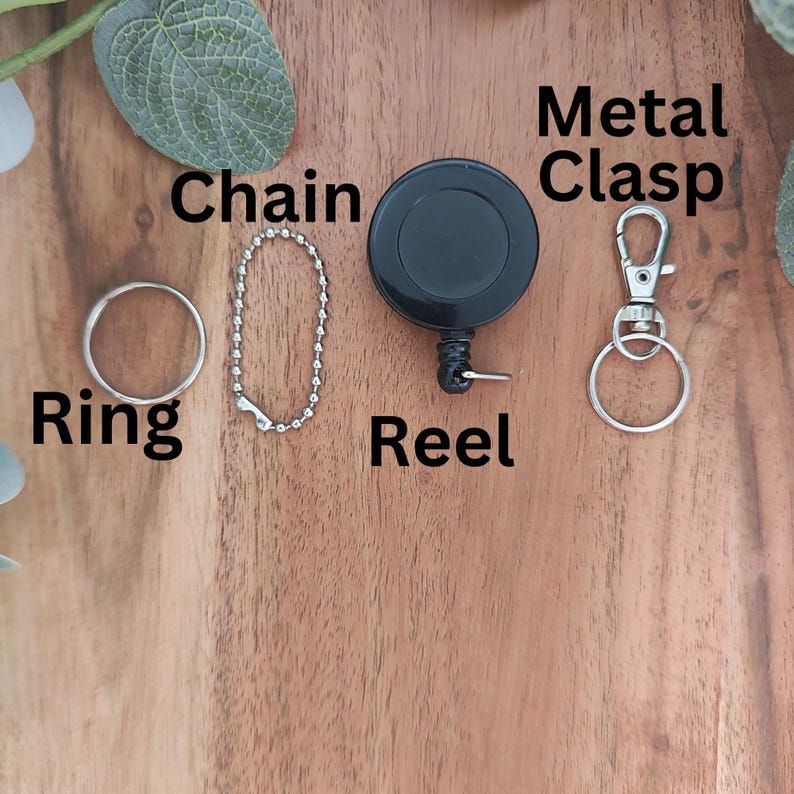 May include: A silver chain, ring, and retractable reel with a black plastic casing. A silver metal clasp is also included.