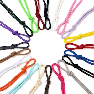 May include: A selection of colourful, adjustable cords with loops and knots. The cords are in various colours, including green, purple, brown, white, orange, and pink. The cords are arranged in a circular pattern against a white background.