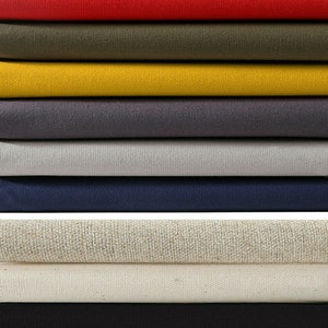 May include: A stack of 100% cotton canvas fabric in 7 colors: beige, red, olive green, yellow, gray, light gray, navy blue, natural, and black. The fabric is 16 ounce heavy weight upholstery fabric.