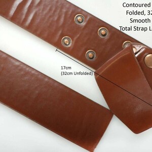 K&ouml;nnte beinhalten: Ein braunes Lederband mit einem konturierten Abschnitt, der 17 cm lang ist, wenn er gefaltet ist, und 32 cm lang, wenn er ausgeklappt ist. Das Band hat auch einen glatten Abschnitt, der 79 cm lang ist. Die Gesamtl&auml;nge des Bandes betr&auml;gt 111 cm.