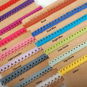 May include: A variety of colorful decorative ribbons are displayed on brown cards. Colors include red, violet, purple, cerise, pink, light lavender, charcoal, grey, white, brick, dark blue, bright blue, lime green, sage green, and yellow. The text "AMAZING RIBBONS" is visible.