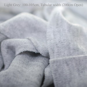 May include: Close-up of a light gray fabric with a tubular width of 200cm open. The fabric is 100-105cm long.