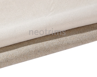 Pode incluir: Duas peças de tecido, uma branca e outra bege, estão dobradas uma sobre a outra. O tecido branco está na parte superior e tem uma textura lisa. O tecido bege está por baixo e tem uma textura mais áspera.