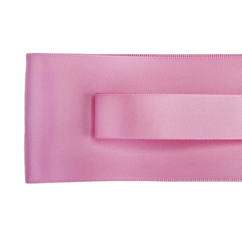 May include: A pink satin ribbon with a textured surface.
