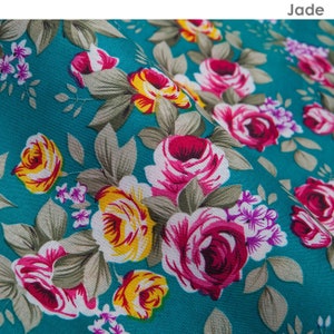 K&ouml;nnte beinhalten: Ein blaugr&uuml;ner Stoff mit einem Blumenmuster mit rosa, gelben und wei&szlig;en Rosen. Der Stoff hat eine strukturierte Oberfl&auml;che.