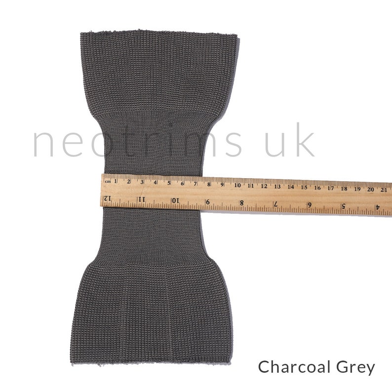 Puede incluir: Tejido de punto gris antracita con textura acanalada. El tejido se mide con una regla, mostrando un ancho de 10 cm.
