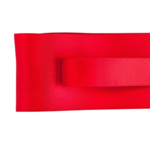 May include: Two pieces of red satin ribbon, one on top of the other.
