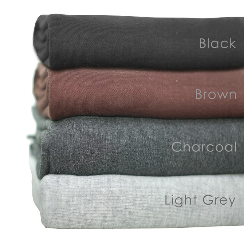 May include: A stack of four fabric swatches in different colors: black, brown, charcoal, and light grey. The swatches are folded and stacked on top of each other.
