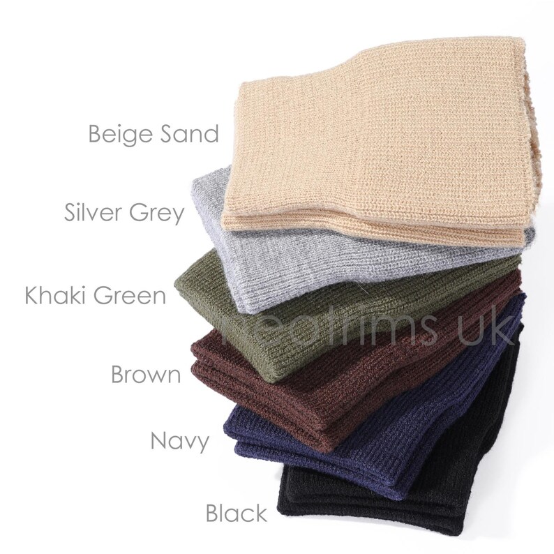 May include: A stack of knitted headbands in various colors, including beige sand, silver grey, khaki green, brown, navy, and black. The image displays the product's color options with the names of each color next to the corresponding headband.