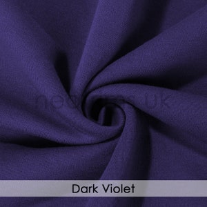 Puede incluir: Primer plano de una tela de color violeta oscuro con una superficie suave y texturizada. La tela est&aacute; doblada y drapeada, mostrando su textura suave.