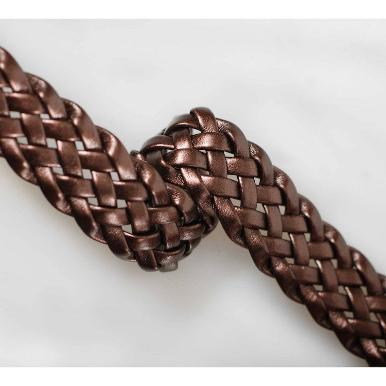 Peut inclure: Un gros plan sur une ceinture en cuir tress&eacute; marron. Le cuir est tiss&eacute; en un motif serr&eacute; et complexe.