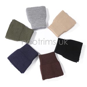 May include: A collection of six wristbands in various colors, including olive green, gray, tan, black, navy blue, and brown. The wristbands are made of a knitted material and are arranged in a circular pattern. The text "neotrims UK" is visible.