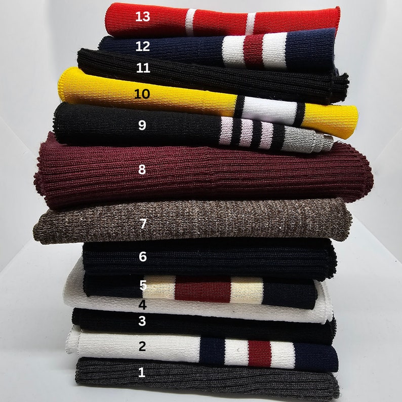 Peut inclure: Un empilement de 13 &eacute;chantillons de tissu tricot&eacute; diff&eacute;rents, chacun avec une couleur et un motif diff&eacute;rents. Les &eacute;chantillons sont num&eacute;rot&eacute;s de 1 &agrave; 13, le haut &eacute;tant le num&eacute;ro 13 et le bas le num&eacute;ro 1.