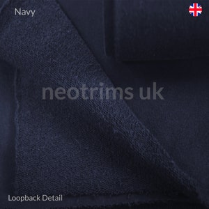 Puede incluir: Primer plano de tejido de bucle azul marino. El tejido es suave y texturizado, con un detalle de bucle visible en la parte inferior. El texto "neotrims uk" es visible en la imagen.