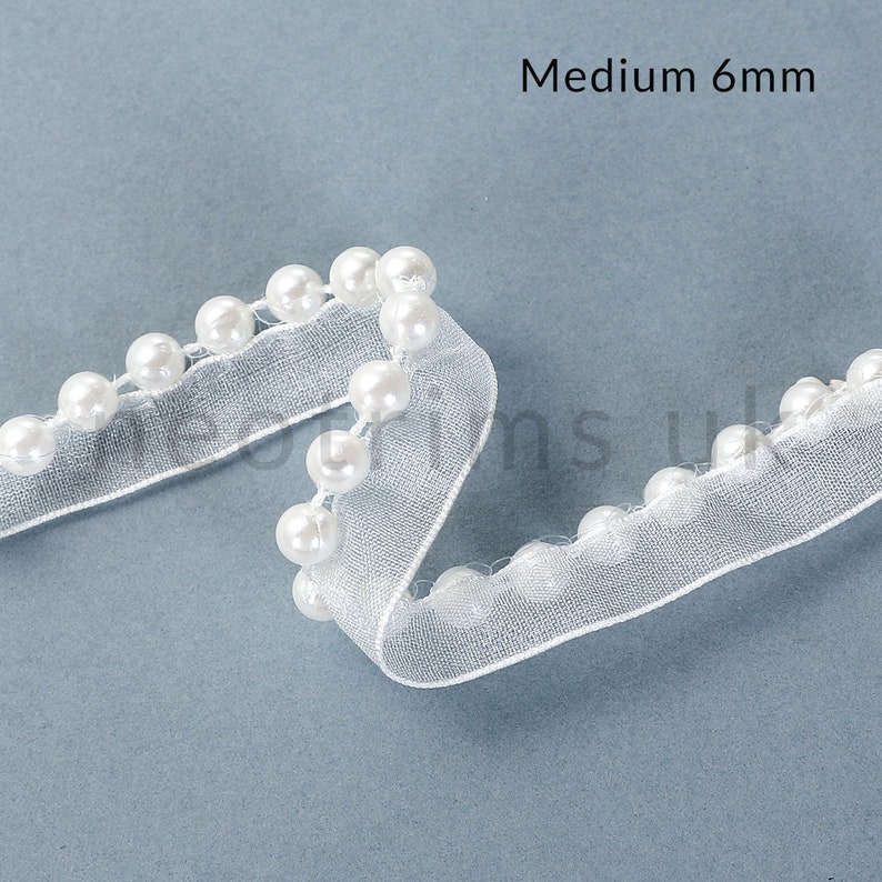 May include: White pearl trim ribbon with a sheer, mesh backing. The ribbon is 6mm wide and has a medium size pearl.
