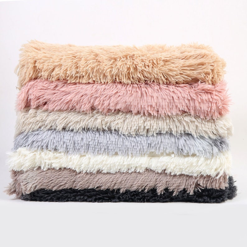 Puede incluir: Una pila de seis muestras de tela de piel sint&eacute;tica esponjosa en varios colores, incluyendo beige, rosa, gris, blanco, marr&oacute;n y negro.