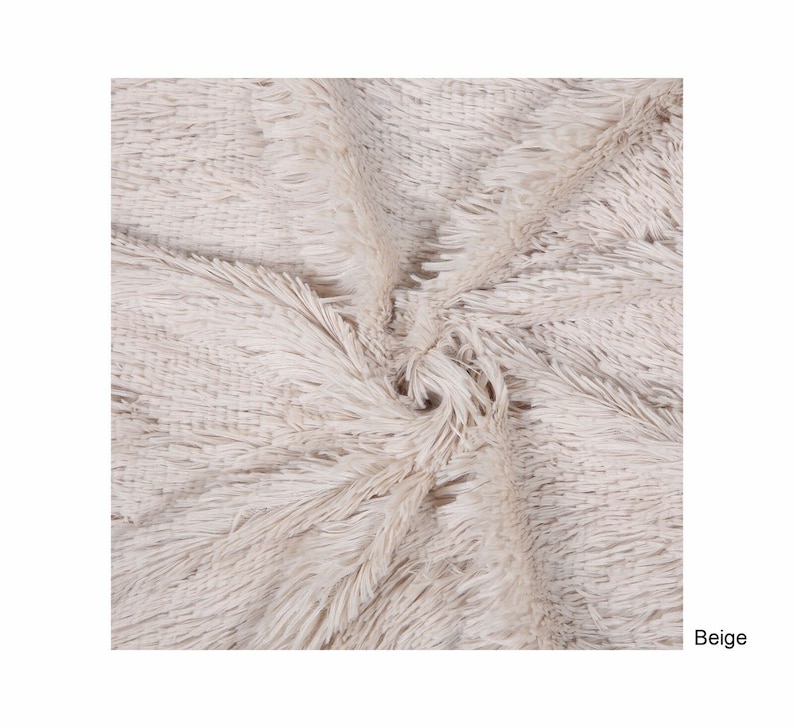 Puede incluir: Primer plano de una alfombra esponjosa beige con una textura suave y peluda. La alfombra est&aacute; hecha de un material de alta calidad y es perfecta para agregar un toque de calidez y comodidad a cualquier habitaci&oacute;n.