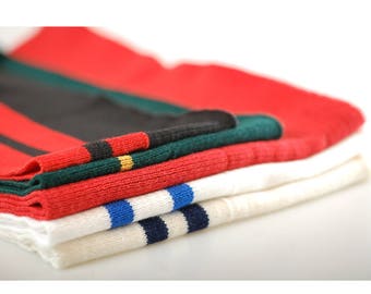 May include: A stack of folded fabric with red, black, green, white, and blue stripes. The fabric is folded in a neat pile.