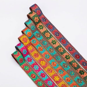 May include: Assortment of colourful embroidered trim with floral patterns and gold accents. The trim is arranged in a fan shape, with the widest piece at the top and the narrowest piece at the bottom.