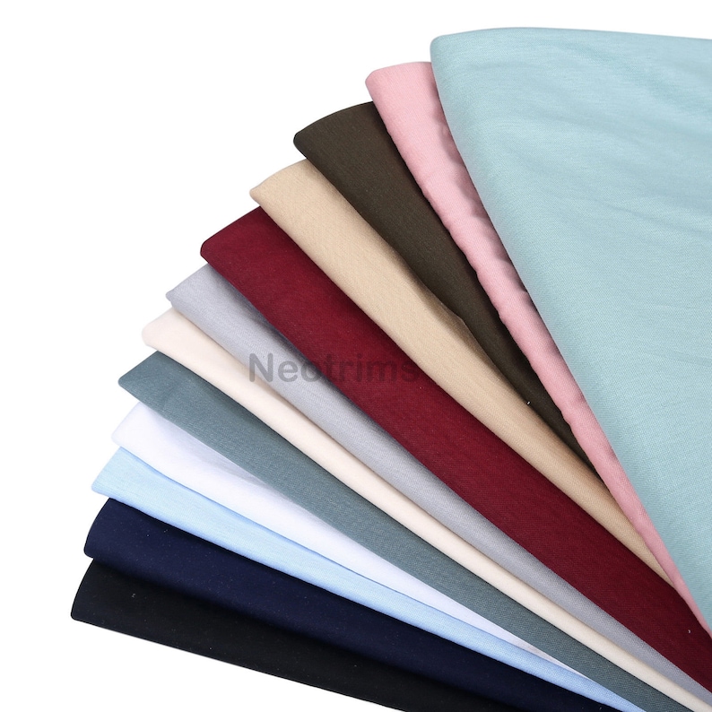 May include: A stack of ten fabric swatches in various colors, including black, navy blue, light blue, white, gray, burgundy, beige, olive green, pink, and light blue.