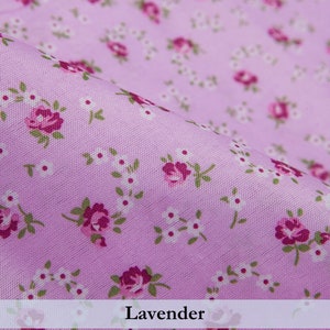 Puede incluir: Un primer plano de una tela de color lavanda con un peque&ntilde;o patr&oacute;n floral blanco y rosa. La tela es lisa y tiene un brillo sutil.