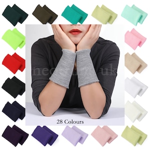 May include: A variety of wrist warmers in 28 colors, including green, gray, pink, and black. The image shows a person wearing gray wrist warmers, with other colors displayed around them. The text "28 Colours" is visible.