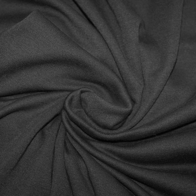 May include: Close-up of a black fabric with a soft, textured surface. The fabric is folded and draped, creating a smooth, flowing look.