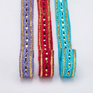 May include: Three different trims of fabric with gold accents. The trims are purple, red, and turquoise.