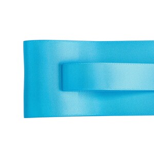 May include: A close-up of a bright blue satin ribbon folded in half. The ribbon is smooth and has a subtle sheen.