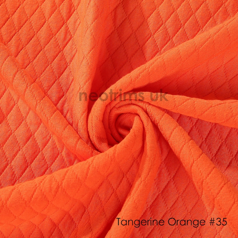 May include: Close-up of a bright orange fabric with a textured diamond pattern. The fabric is soft and has a slight sheen. The text "Tangerine Orange #35" is printed at the bottom of the image.