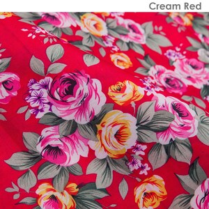 K&ouml;nnte beinhalten: Roter Stoff mit einem floralen Muster mit rosa, gelben und gr&uuml;nen Rosen. Der Stoff hat eine strukturierte Oberfl&auml;che.