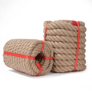 May include: Two bundles of thick, natural-coloured rope, tightly wound and secured with bright red bands. One bundle is cylindrical, while the other is stacked. The rope appears to be made of a coarse, durable material.