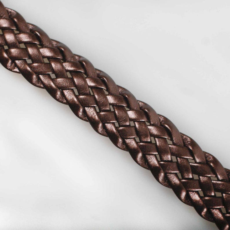 Peut inclure: Un gros plan sur une ceinture tress&eacute;e en cuir marron. La ceinture est tiss&eacute;e selon un motif serr&eacute; et complexe.