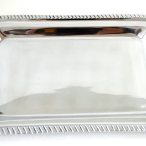May include: A silver serving tray with a decorative border and two blue and white ceramic handles.