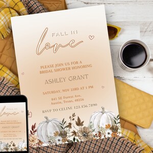 May include: A bridal shower invitation with a fall theme. The invitation features the words "Fall in Love" in elegant script, along with details for Ashley Grant's shower. The design includes pumpkins and floral elements in warm autumn colors. A smartphone displays the same invitation.