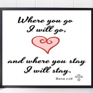 May include: A black framed print with a white background and black text that reads "Where you go I will go, and where you stay I will stay."  The text is in a cursive font. There is a pink heart with a swirl in the center of the print. The text "Ruth 1:16" is below the heart. A small cross is to the right of the text.