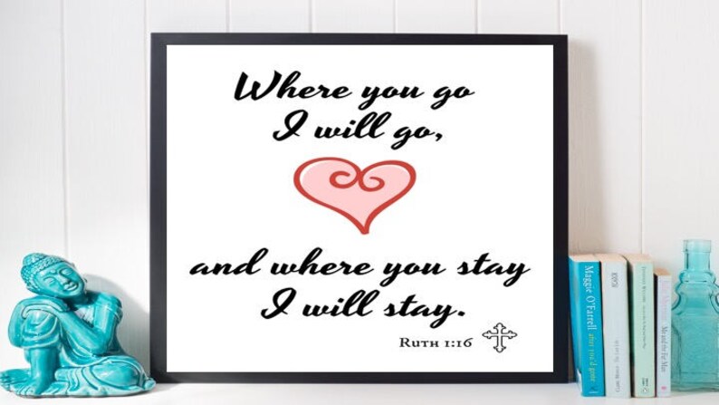 May include: A black framed print with a white background and black text that reads "Where you go I will go, and where you stay I will stay."  The text is in a cursive font. There is a pink heart with a swirl in the center of the print. The text "Ruth 1:16" is below the heart. A small cross is to the right of the text.