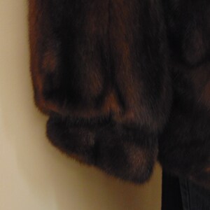 May include: A brown fur coat with a long sleeve. The fur is soft and fluffy.