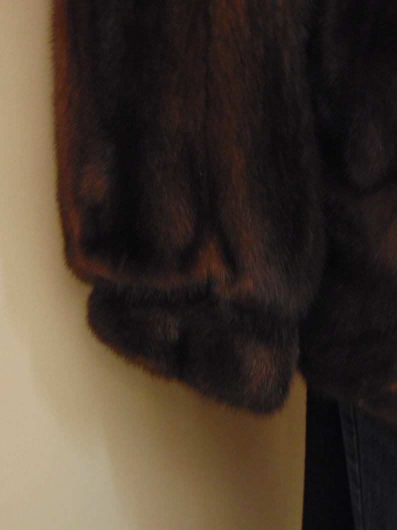 May include: A brown fur coat with a long sleeve. The fur is soft and fluffy.