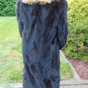 May include: A long black fur coat with a chevron pattern. The coat is made of a soft, luxurious fur.