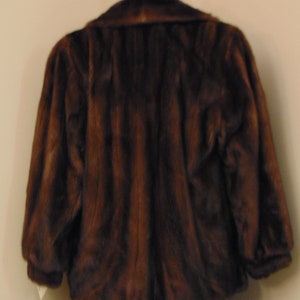 May include: A brown fur jacket with a collar and long sleeves.