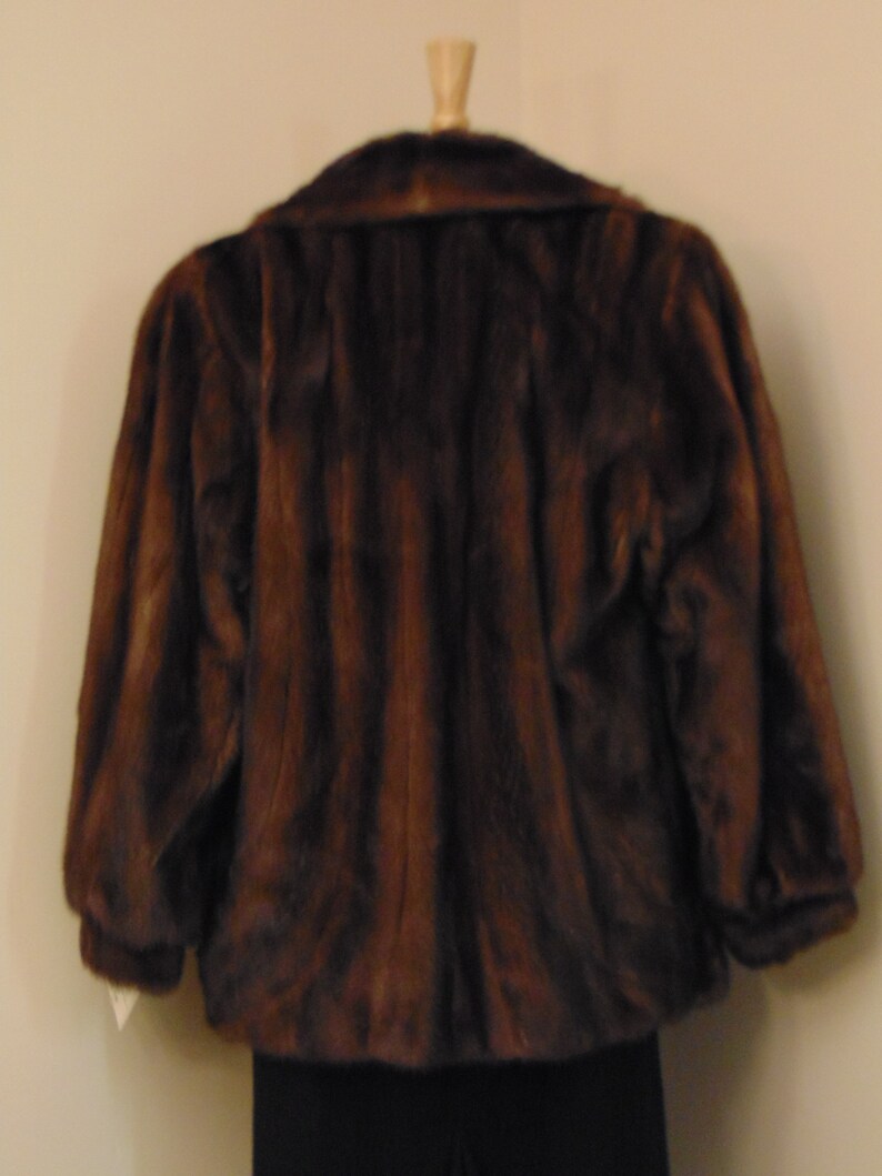 May include: A brown fur jacket with a collar and long sleeves.