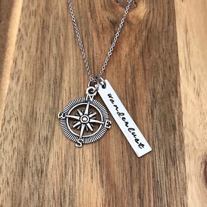 May include: Silver necklace with a compass charm and a pendant that says "wanderlust".