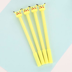 May include: Four yellow pens featuring a character topper with a yellow head, pointed ears with black tips, black eyes, and red circular cheeks. Each pen has a matching yellow cylindrical barrel and a removable yellow cap at the bottom end.