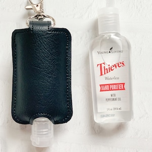 May include: A black leather keychain with a clear plastic bottle of Thieves Waterless Hand Purifier with Peppermint Oil by Young Living. The bottle is 1 fl. oz. (29.56 ml).