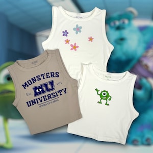 May include: Three sleeveless crop tops. One is tan with "Monsters University" text. Another is white with a green cartoon character. The third is white with pink and purple flower graphics. All have the brand name "RUYA".